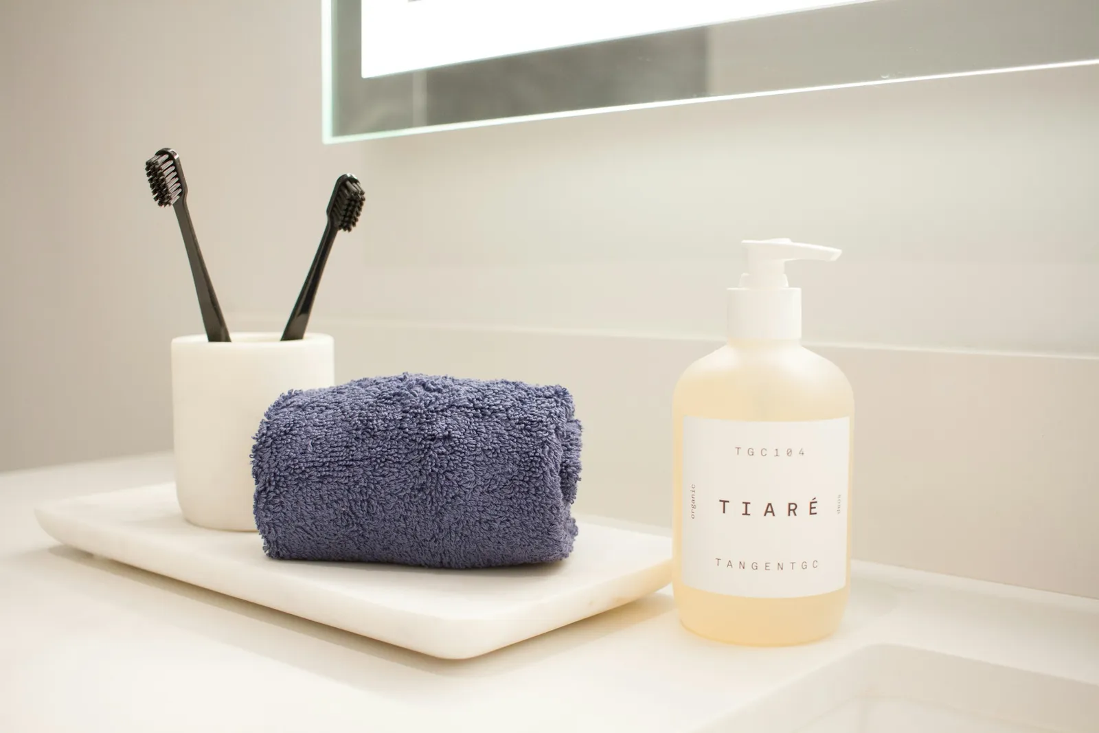 Plan de vasque avec deux brosses à dents dans un gobelet, une serviette roulée et un flacon de savon