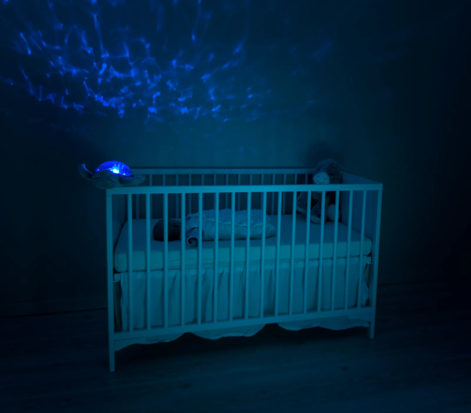 Chambre d'enfant dans la pénombre, lit à barreaux éclairé par une veilleuse bleue
