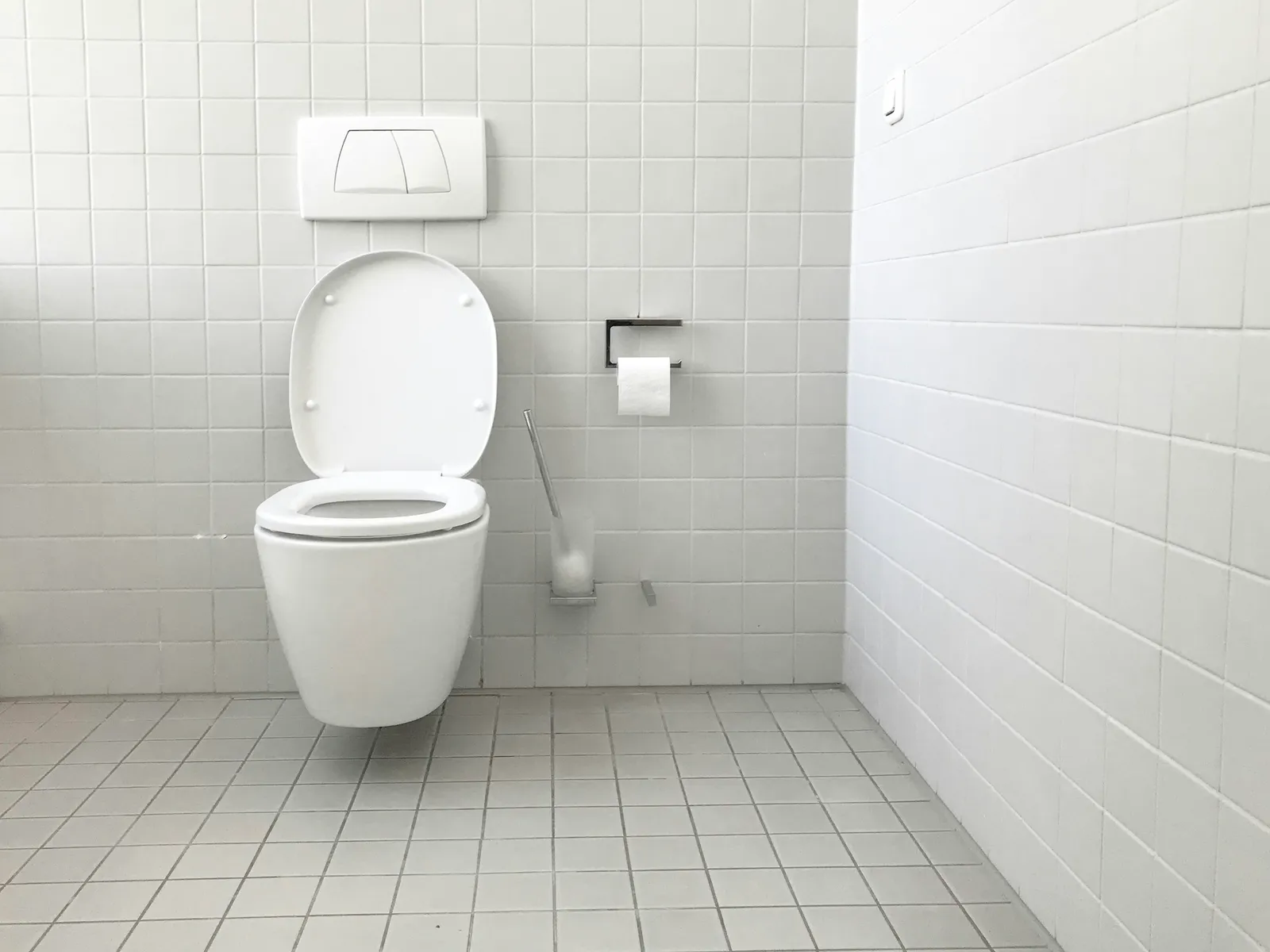 Toilettes suspendues dans une salle de bains carrelée de blanc