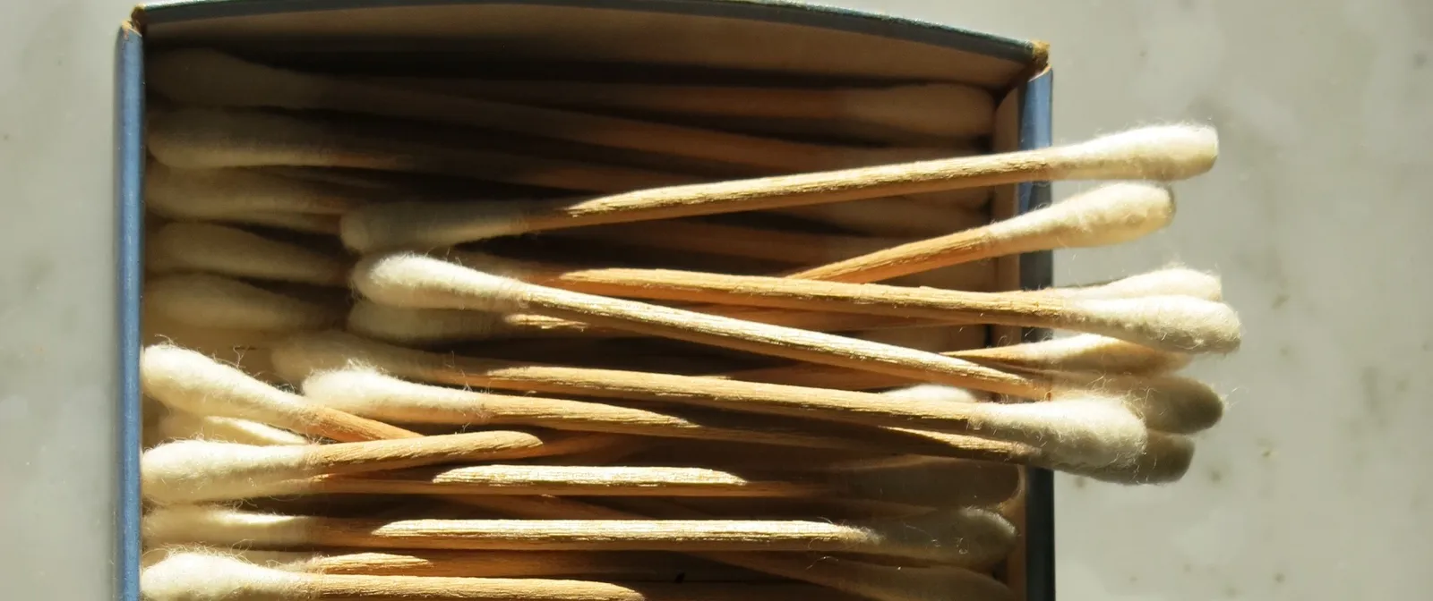 Boîte en carton ouverte remplie de cotons-tiges à tige en bois, posée sur un plan de travail clair