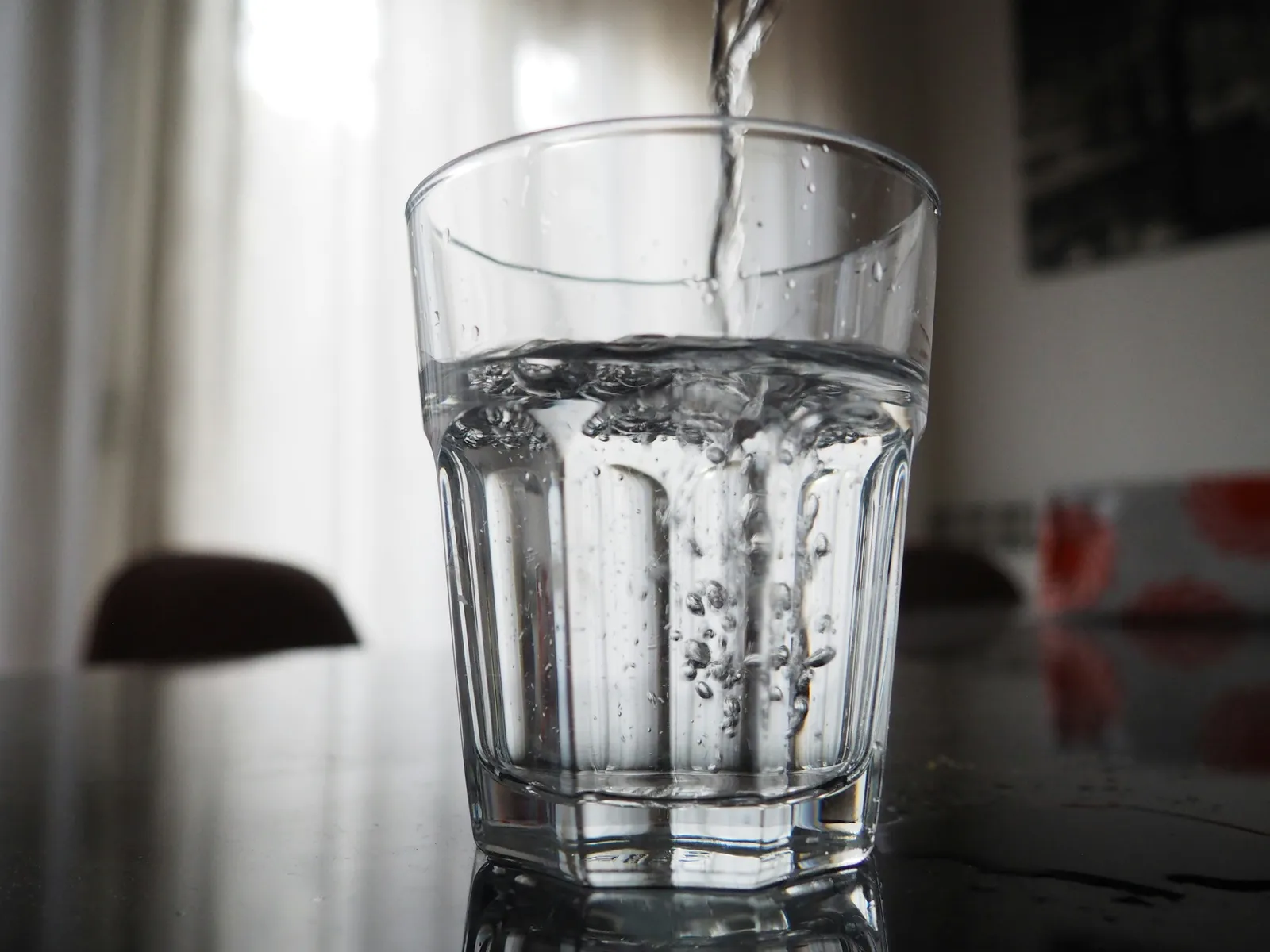 Eau versée dans un verre transparent posé sur une table