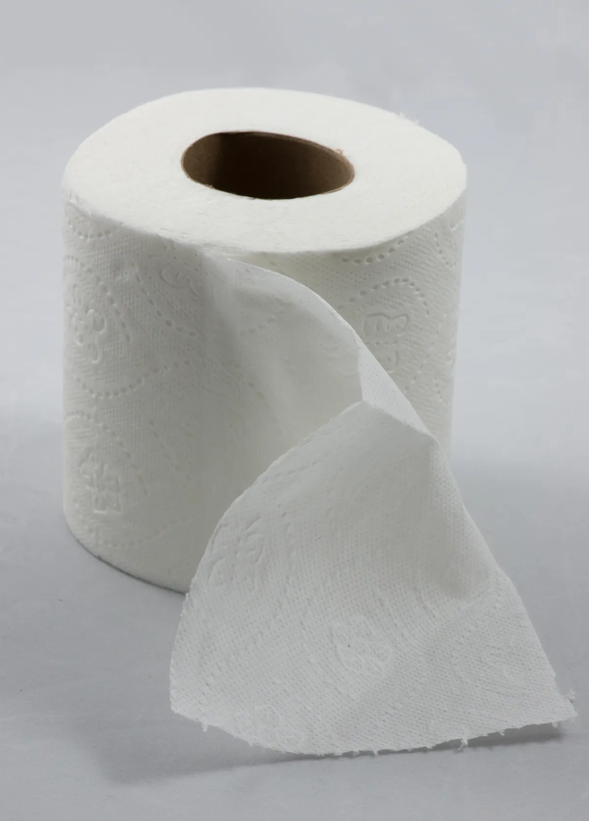 Rouleau de papier toilette blanc posé debout, la première feuille déroulée vers l'avant